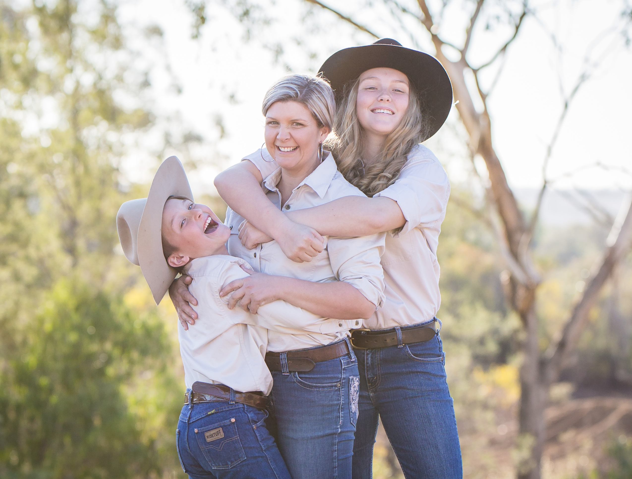 A lady and her two daughters on a farm smiling.